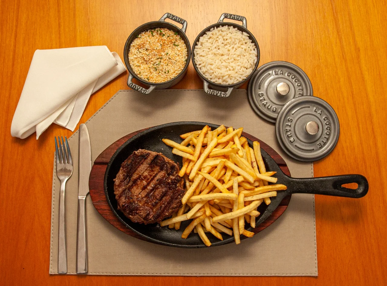 Carne e batatas fritas na frigideira com acompanhamentos — fotografia de Ulysses Paiva para Dom Ferreira Forneria